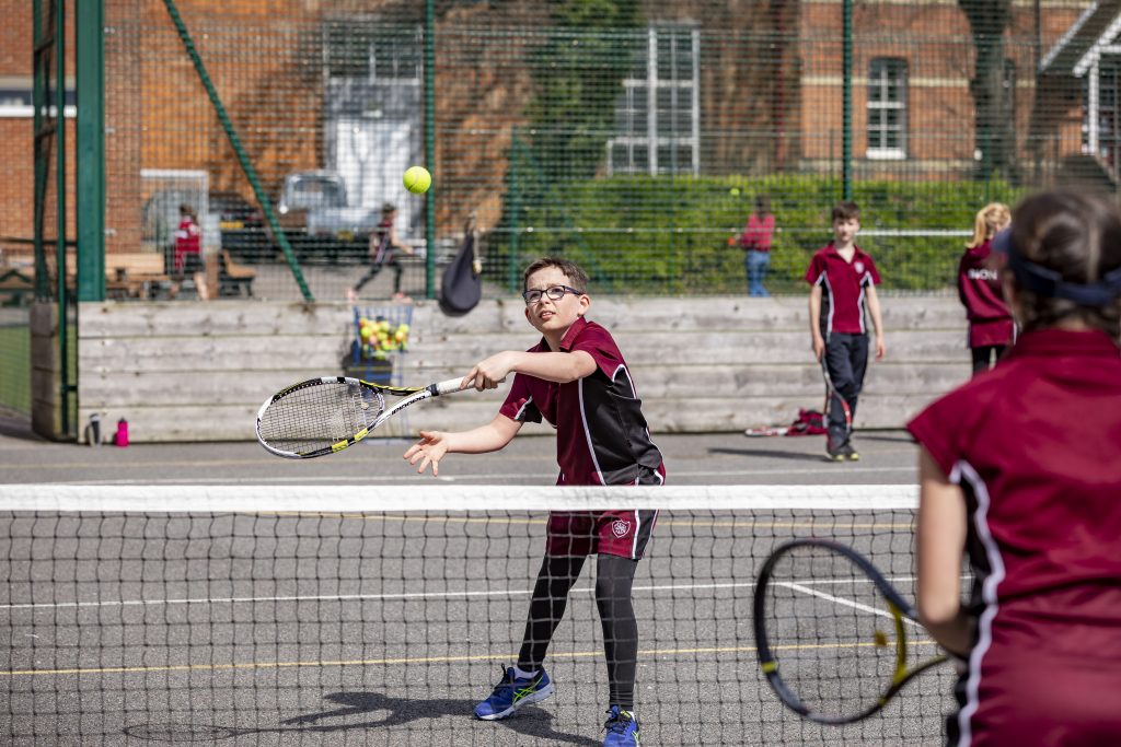 student hitting ball with tennis racquet